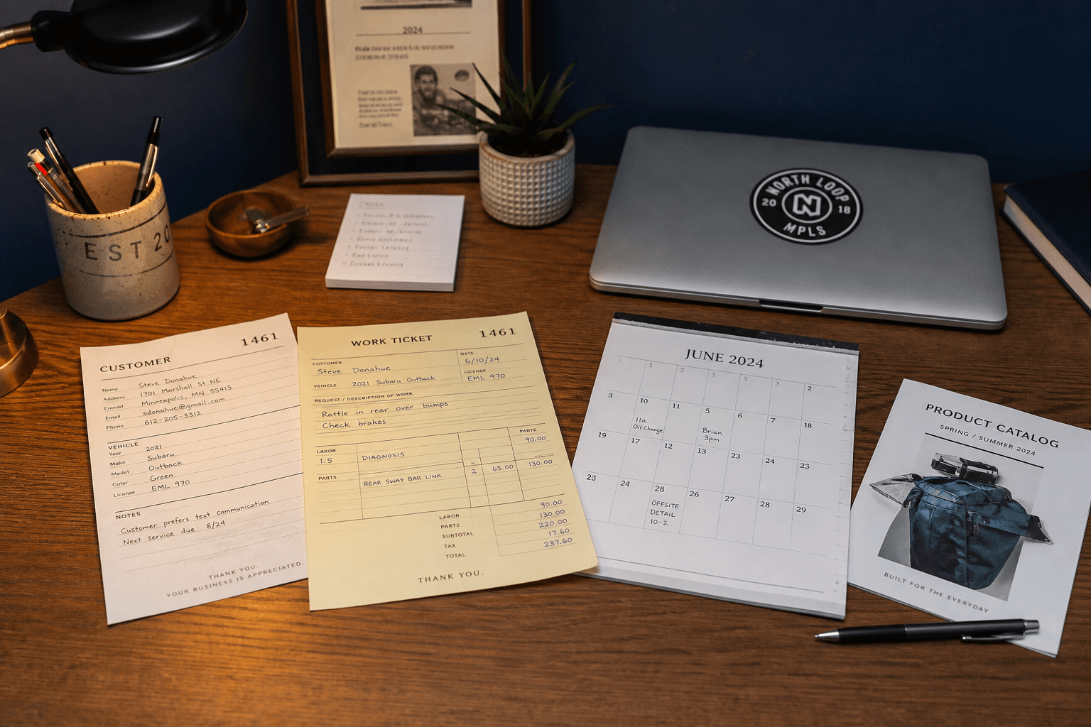 A desk holding a customer card, a work ticket, a calendar page, and a catalog sheet together.